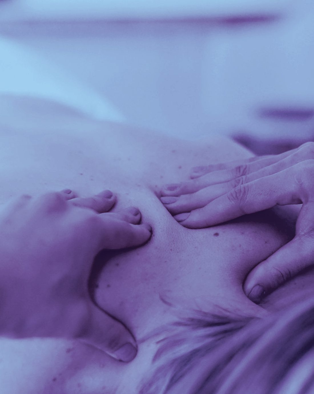 A client resting peacefully as gentle hands work the neck and shoulders, in cool, calm light
